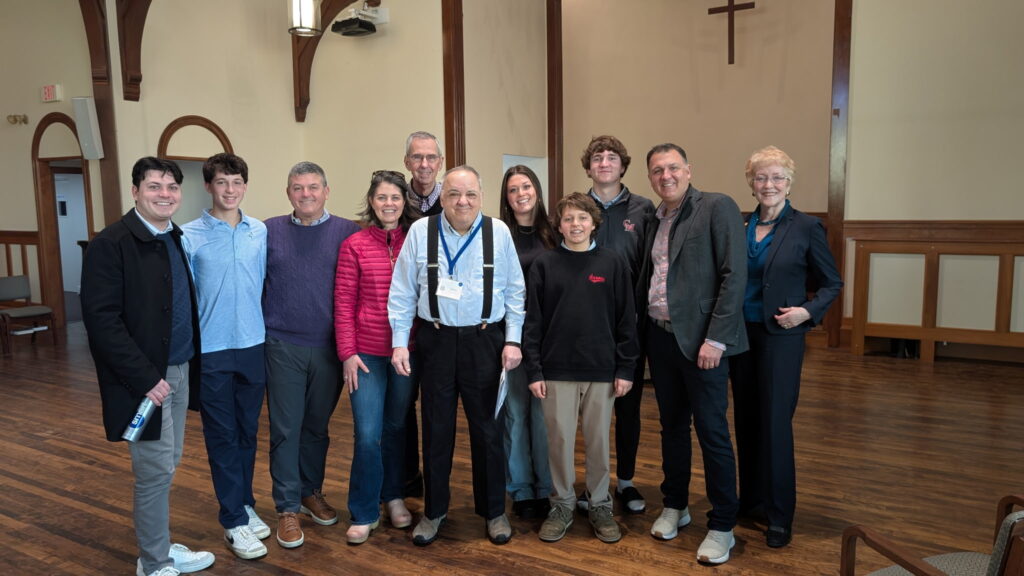 John and nine members of his extended family stand in the front of the Sanctuary with the  wooden wall cross behind them